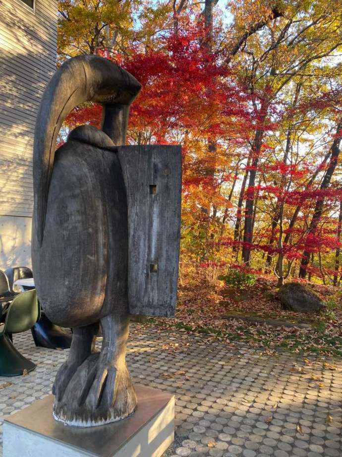 紅葉を背景にしたエントランス横のカラオの像