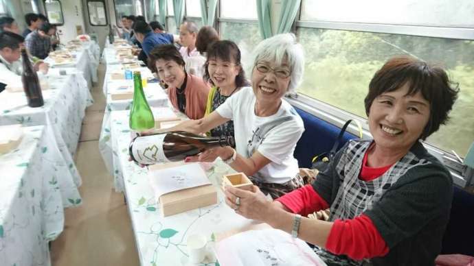 明知鉄道の食堂車内で枡酒を楽しむ人達