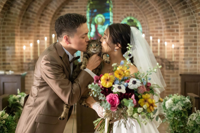 アンジェパティオの結婚式で新郎新婦が愛猫にキスをしている写真