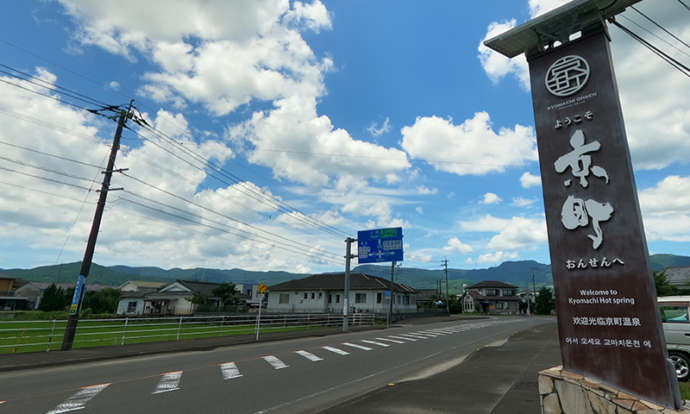 道路沿いの風景と、温泉郷入り口の看板