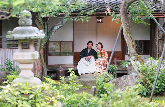 フレンチ奥村邸の縁側で微笑む和装のご夫婦