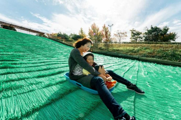 堺市の「ハーベストの丘」で芝すべりを楽しむ親子