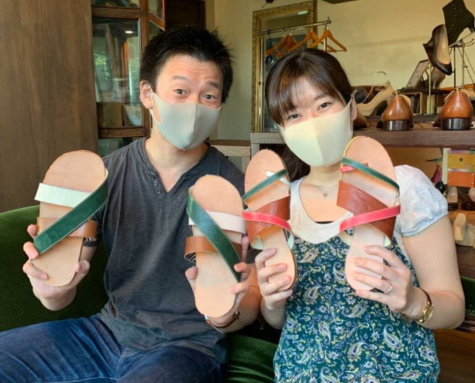 アンティークソファでカラフルなサンダルを掲げるカップル