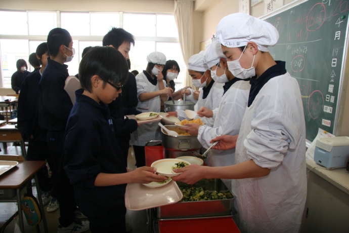 五泉市の小学校で給食をよそっている様子