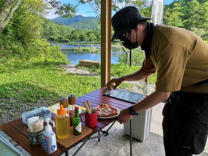 窯焼きピザをカットする平谷湖フィッシングスポットの利用者