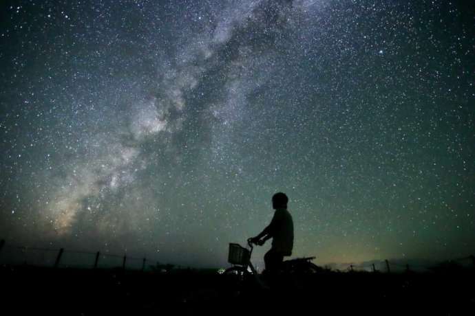 沖縄県石垣市で見える星空と自転車に乗って空を眺める人の写真