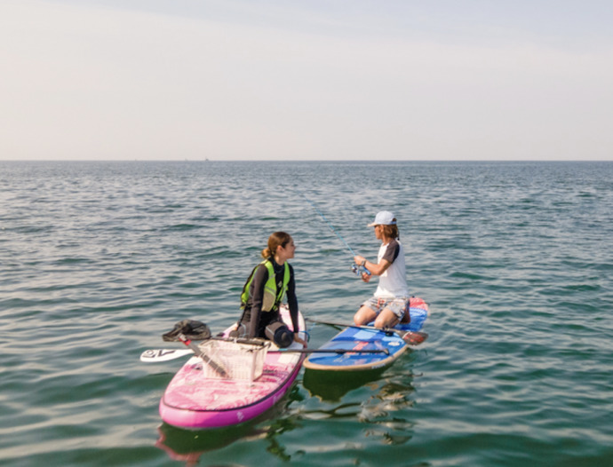 神奈川県茅ヶ崎市の「Hosoii Surf&Sports」でSUPを教わる女性