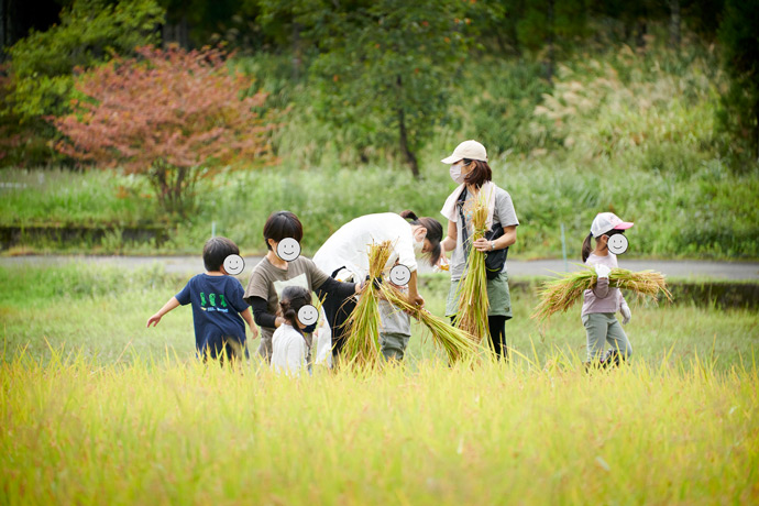 稲刈り作業をする大人と子ども