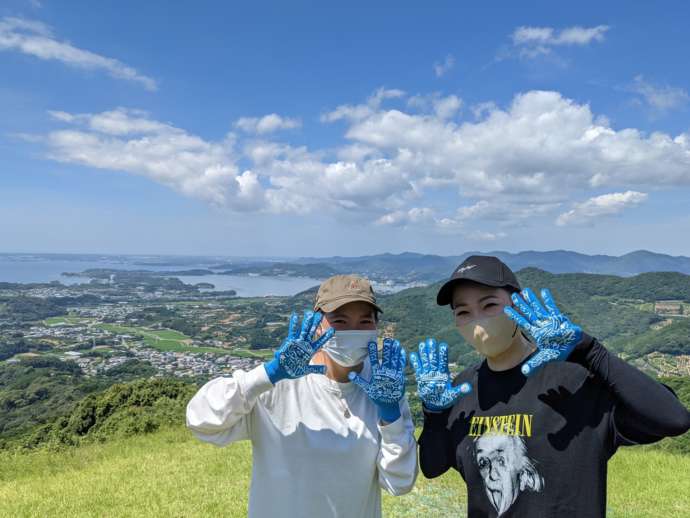 浜名湖パラグライダースクールの体験者が浜名湖を背景に笑顔で手を広げている様子