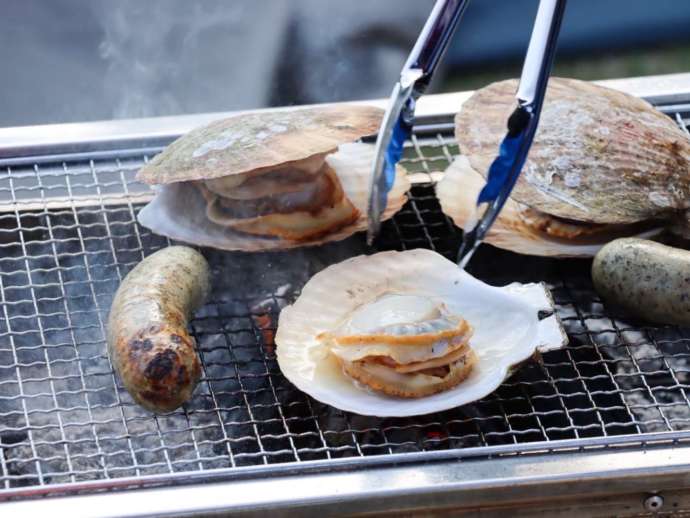 BBQコンロの上で焼かれるホタテとソーセージ