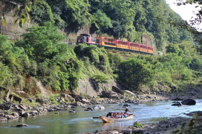 保津川沿いの渓谷を走る嵯峨野トロッコ列車と保津川下りの船