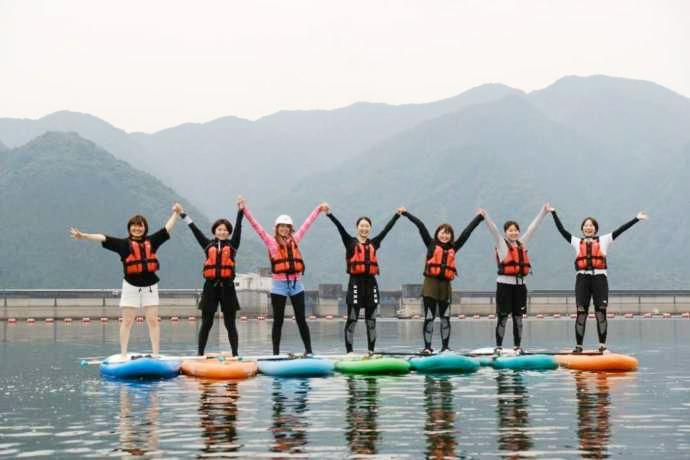 草木湖でSUPをしている女性たちがバンザイで楽しさを表現している写真