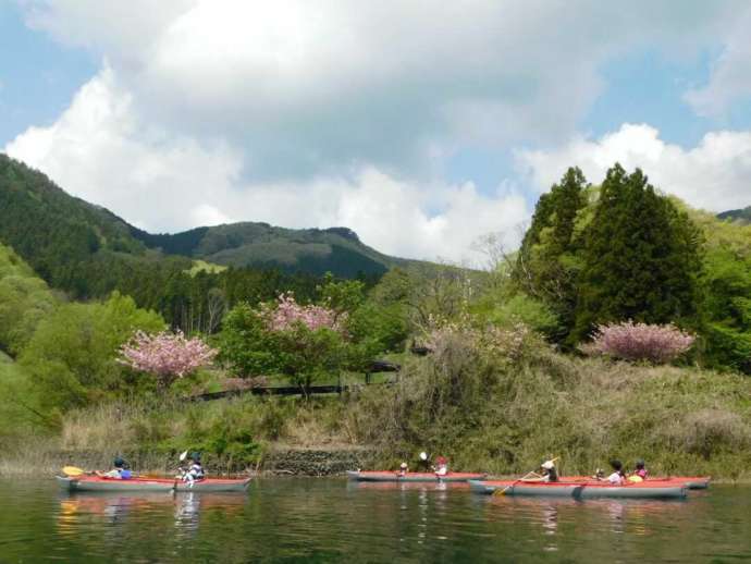 草木湖でカヌーをしているグループと周辺の美しい山々が広がっている風景