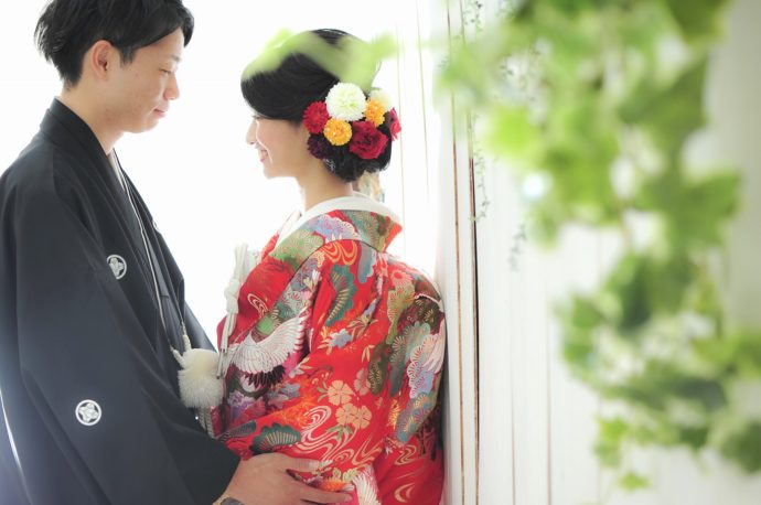 色打掛と羽織袴姿で向き合い微笑む新郎新婦