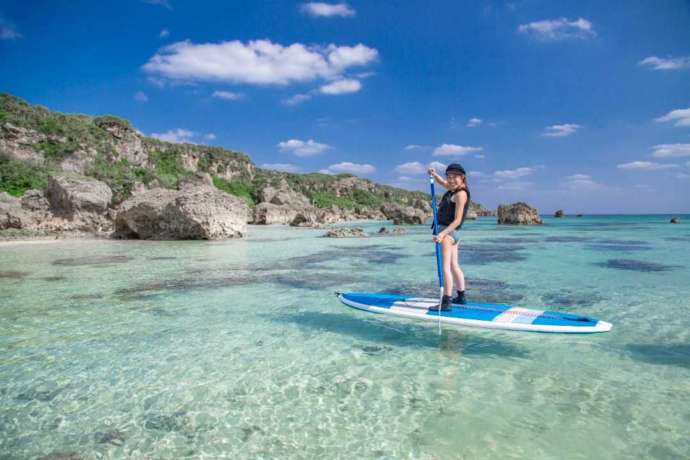 大きなサーフボードに立ち、海の上を進む様子