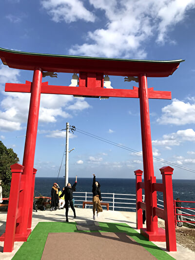 長門市の元乃隅神社の大鳥居の賽銭箱にお賽銭を投げる様子