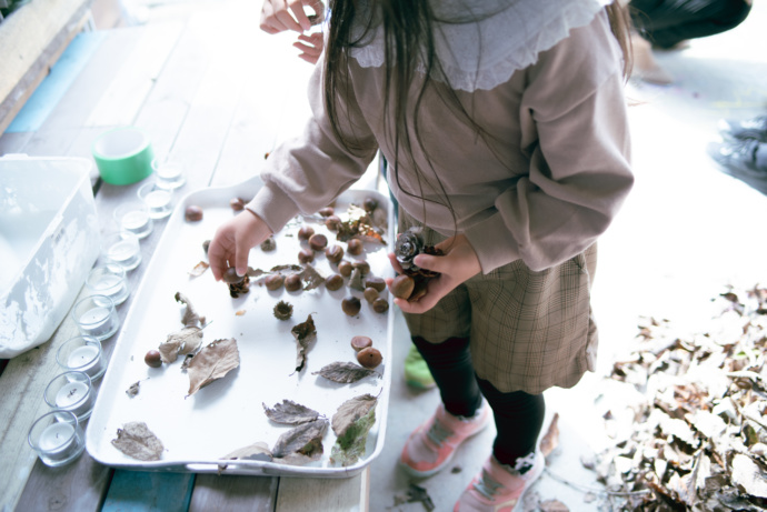 ワークショップで落ち葉やどんぐりを集める子ども