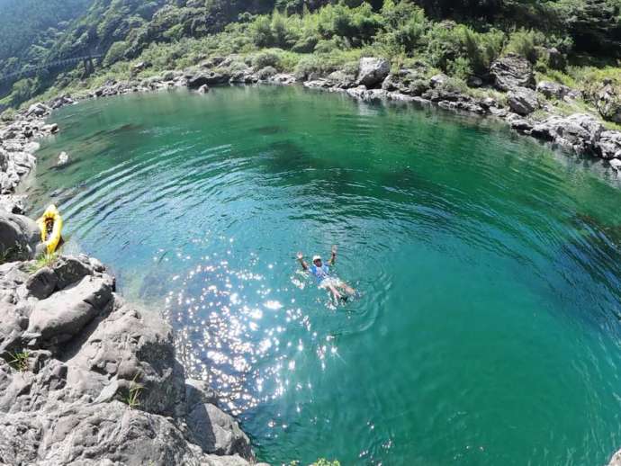 パッククラフト中に岩から川に飛び込み気持ちよさそうに浮かぶ男性