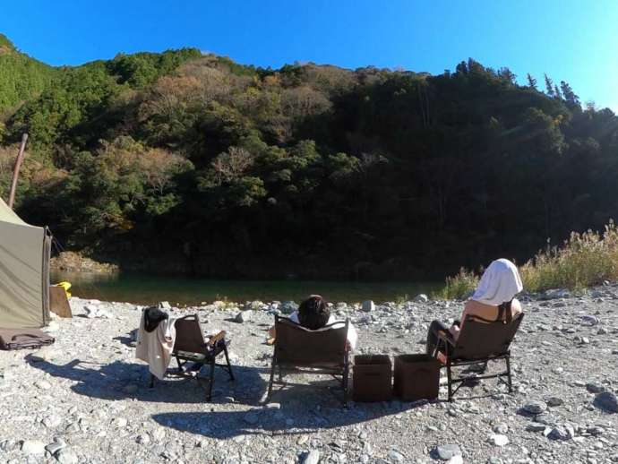 テントサウナ中に河原に腰かけて外気浴中の参加者