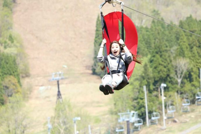 野沢温泉スポーツ公園の「ジップ・スカイライド」を楽しむ女性