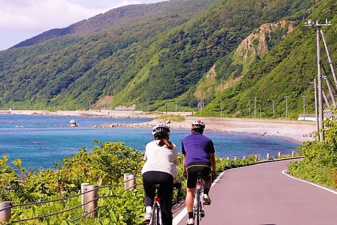 海沿いの道をサイクリングする人々