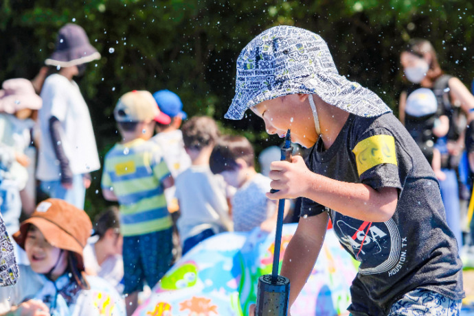 こどもひろばで水遊びをするたくさんの人