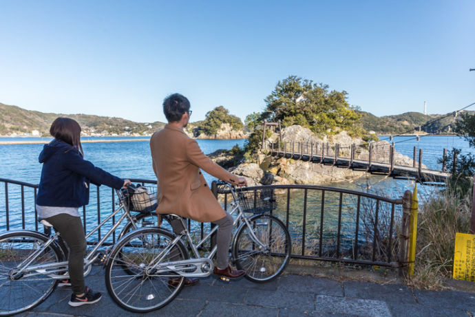 下田市の海沿いを自転車で散策するカップル