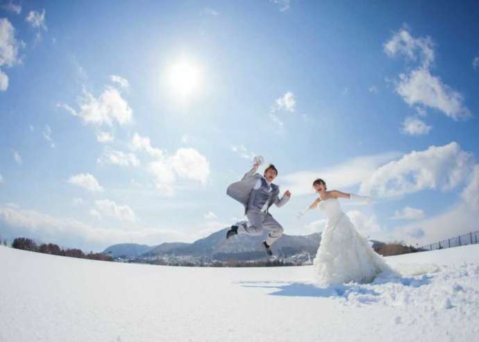 函館山と雪を背景に撮影した洋装でのウェディングフォト