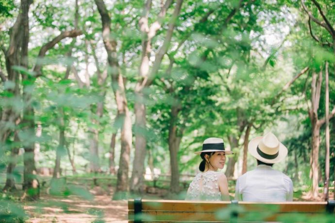 緑あふれる木々とベンチに座る新郎新婦