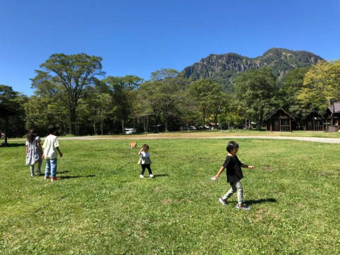 ログキャビンを背景に芝生の上で遊ぶ子ども達