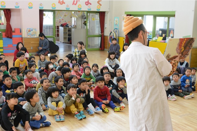 保育園で先生の話を聞く子どもたち