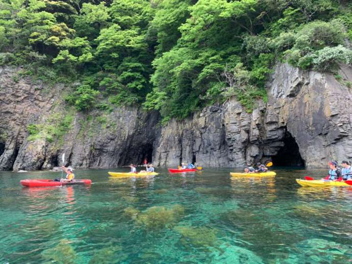 隠岐の島町の崖近くでシーカヤックを楽しむ人々