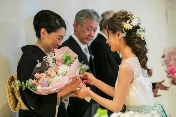 披露宴の結びに、感動しながら母親へ花束を渡す新婦の写真