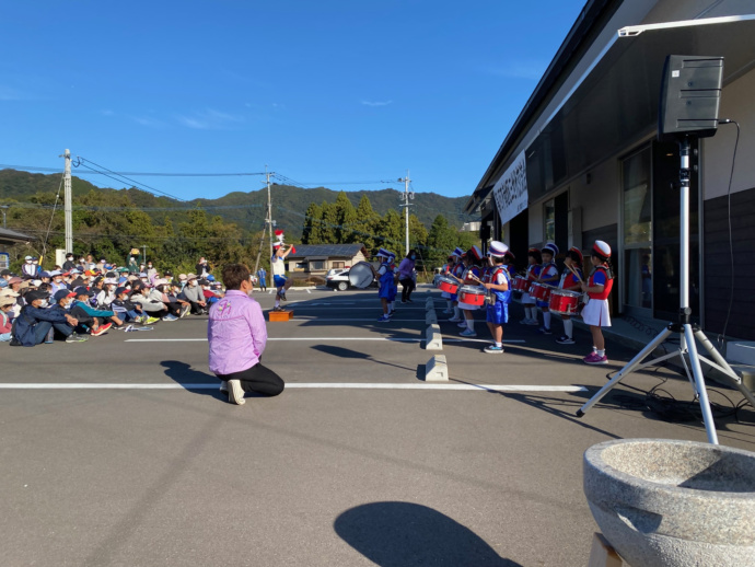 地区交流会でマーチングをする子ども達と、それを見る人々