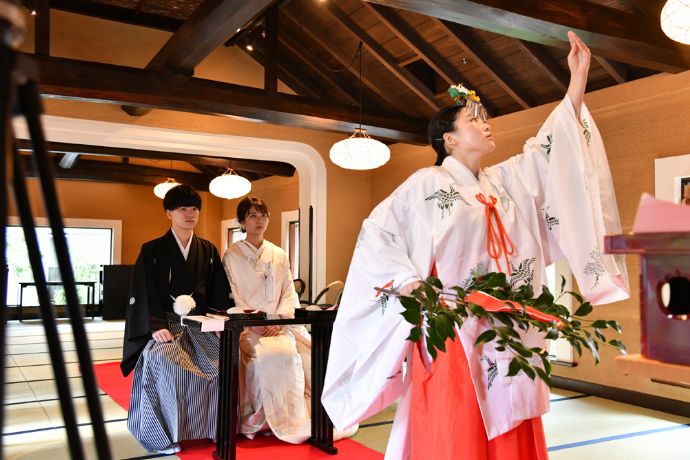 和婚ネットブライダルサロンのオンライン結婚式で巫女の舞を見つめる新郎新婦