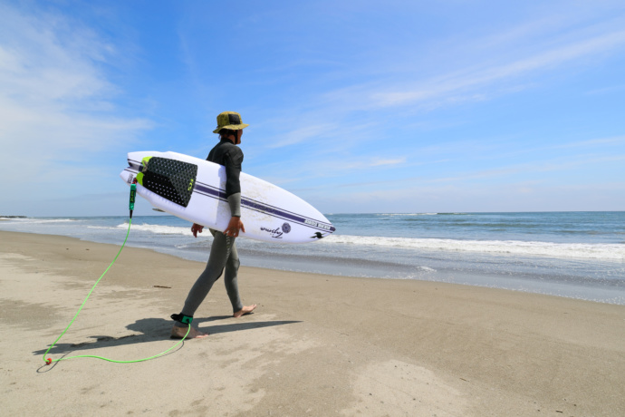 亘理町の海でサーフィンボードを持っている男性