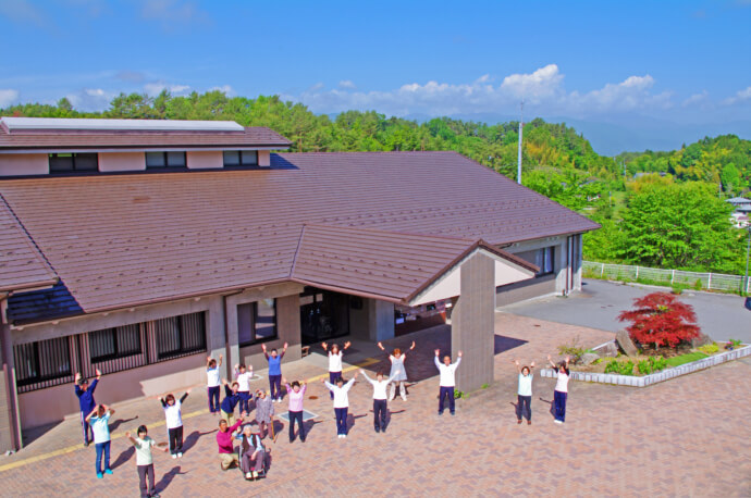 泰阜村保健福祉支援センターの前でポーズとる人々