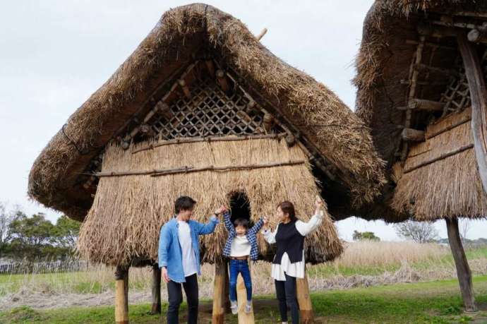 大分県国東市の安国寺集落遺跡公園「弥生のムラ」にある高床建物の前で記念撮影をする家族