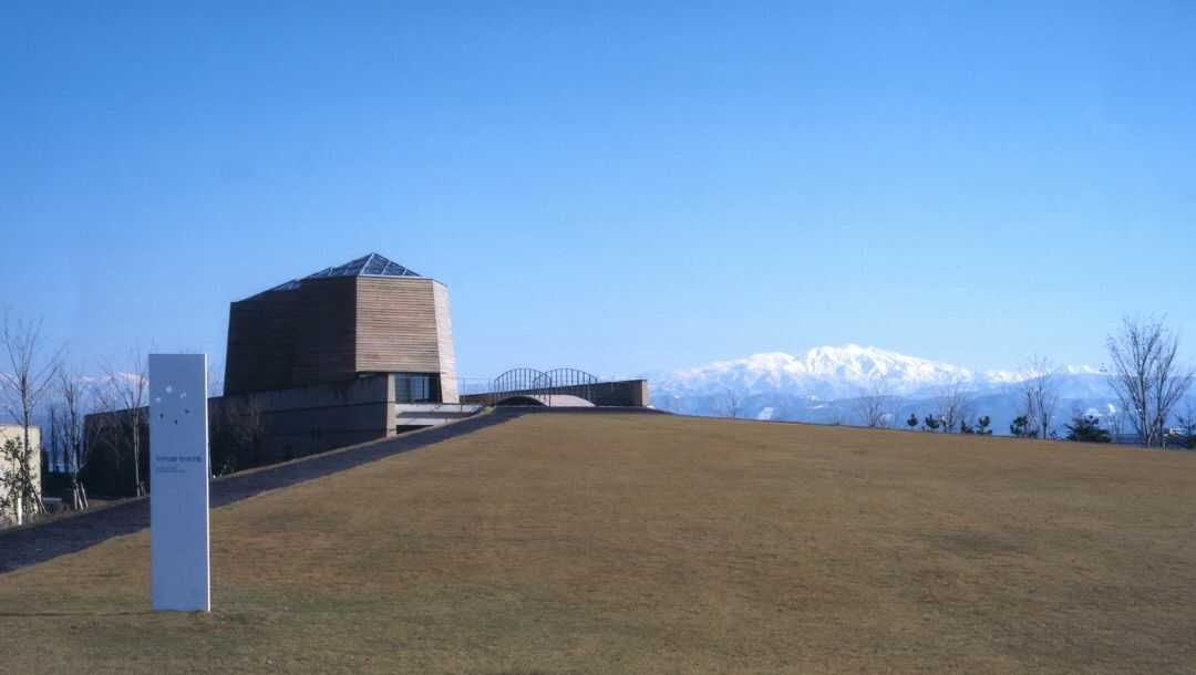 青空の下の「中谷宇吉郎 雪の科学館」建物外観と白山連峰