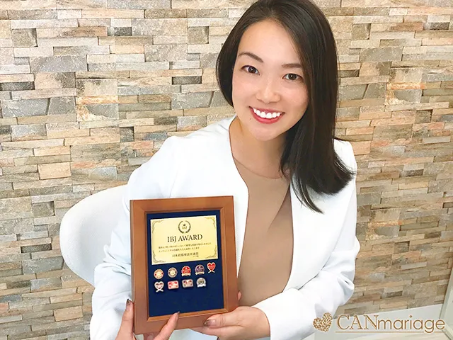 IBJ AWARD受賞記念の盾を持ってほほ笑む坪井さん