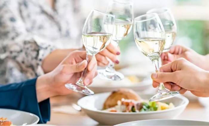 食事中にグラスを合わせて乾杯している人たちの様子