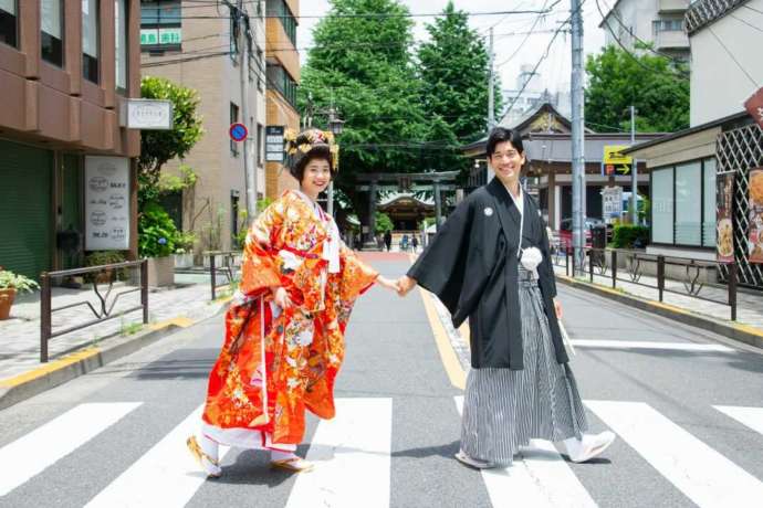 湯島天満宮前の横断歩道を渡る和装の新郎新婦