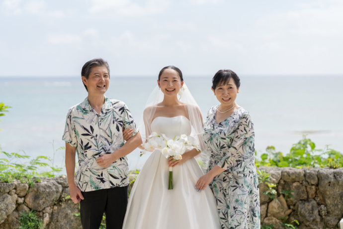 百名伽藍で挙式する花嫁がかりゆしウェアの両親と海をバック撮影した写真