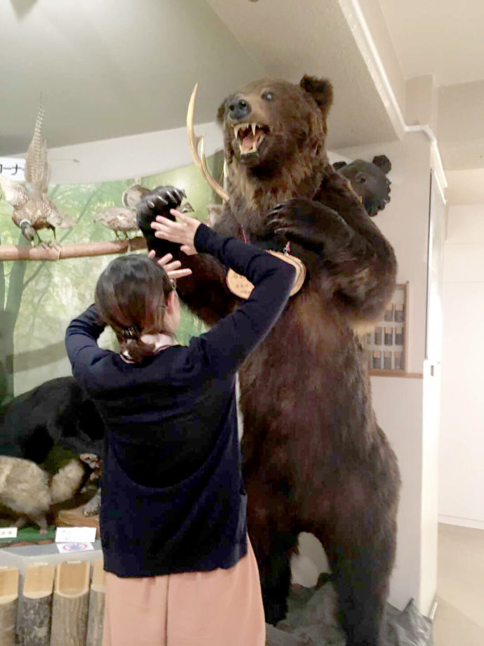 登別市郷土資料館にあるヒグマのはく製の前でびっくりしたようなポーズの学芸員