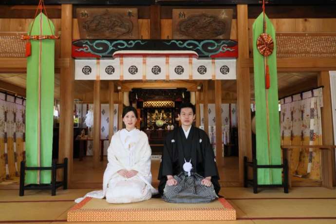 茨城県龍ケ崎市にある「龍ケ崎 八坂神社」の社殿で記念撮影をする新郎新婦