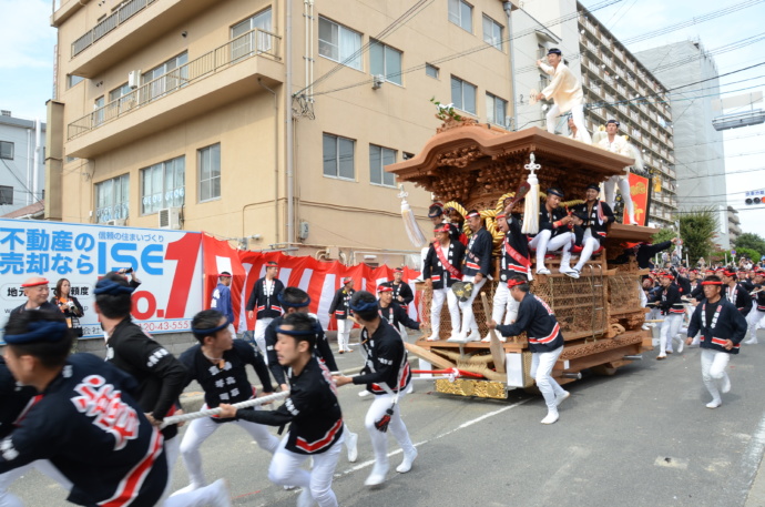 大阪府高石市で大勢の人がだんじりを曳きながら街中を巡行している写真